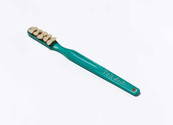 plastic box containing green plastic TEK deluxe toothbrush with the bristles removed and replaced...