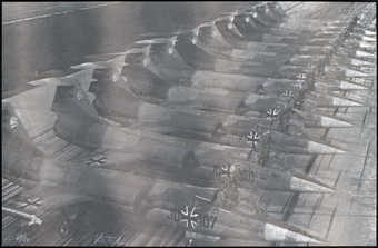 A black and white image of a row of fighter-jets, each with an iron cross visible under the...