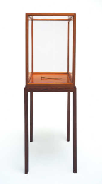 A large iron nail covered with gold leaf.  The nail is displayed in a mahogany virtine, that was...