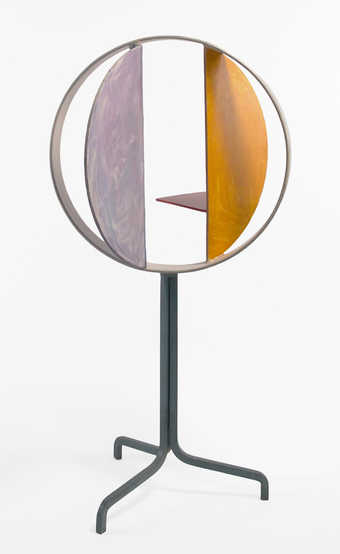 A sculpture composed of painted steel circles and arcs, supported by a single steel tube, that...