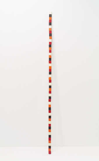 A wooden staff comprised of painted wooden spools glued together
