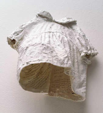 A small plaster dress that hangs on the wall.  Inscriptions are written on the inside of the dress