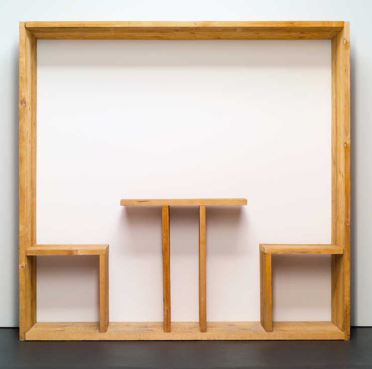 A table and two chairs built within a wooden frame, that is displayed against a wall.