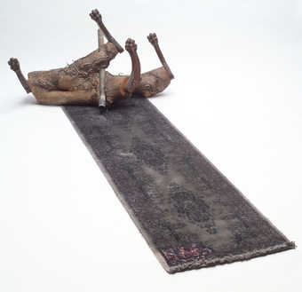 The trunk of a tree that grew around a pole and section of chain-link fence that has been cut and...