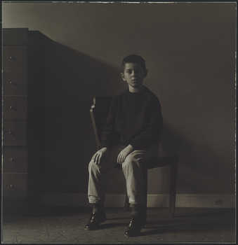 Image of a boy sitting in a chair staring at the camera