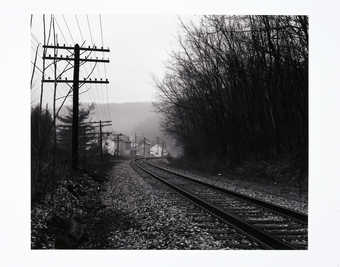 An image of railroad tracks with buildings in the distance