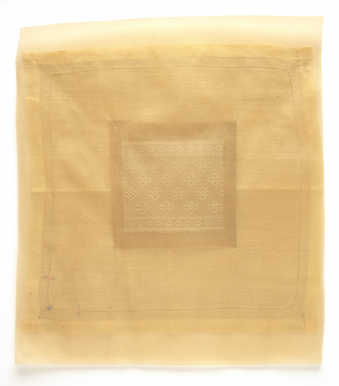 A square piece of lace mounted  to the back of a larger rectangular piece of translucent fabric.