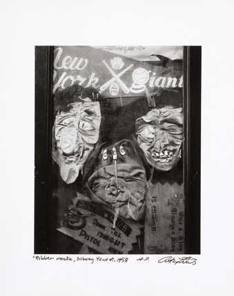 An image of rubber masks smashed up against a store front window.