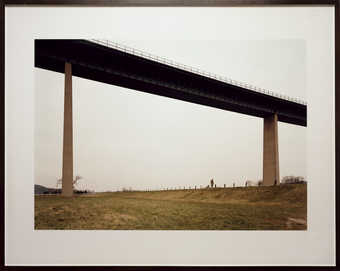 An image of a watercolor artist walking under a large bridge.