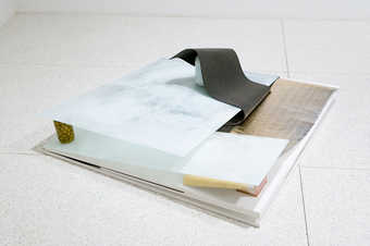 Layers of material balanced and separated by cans and jars.